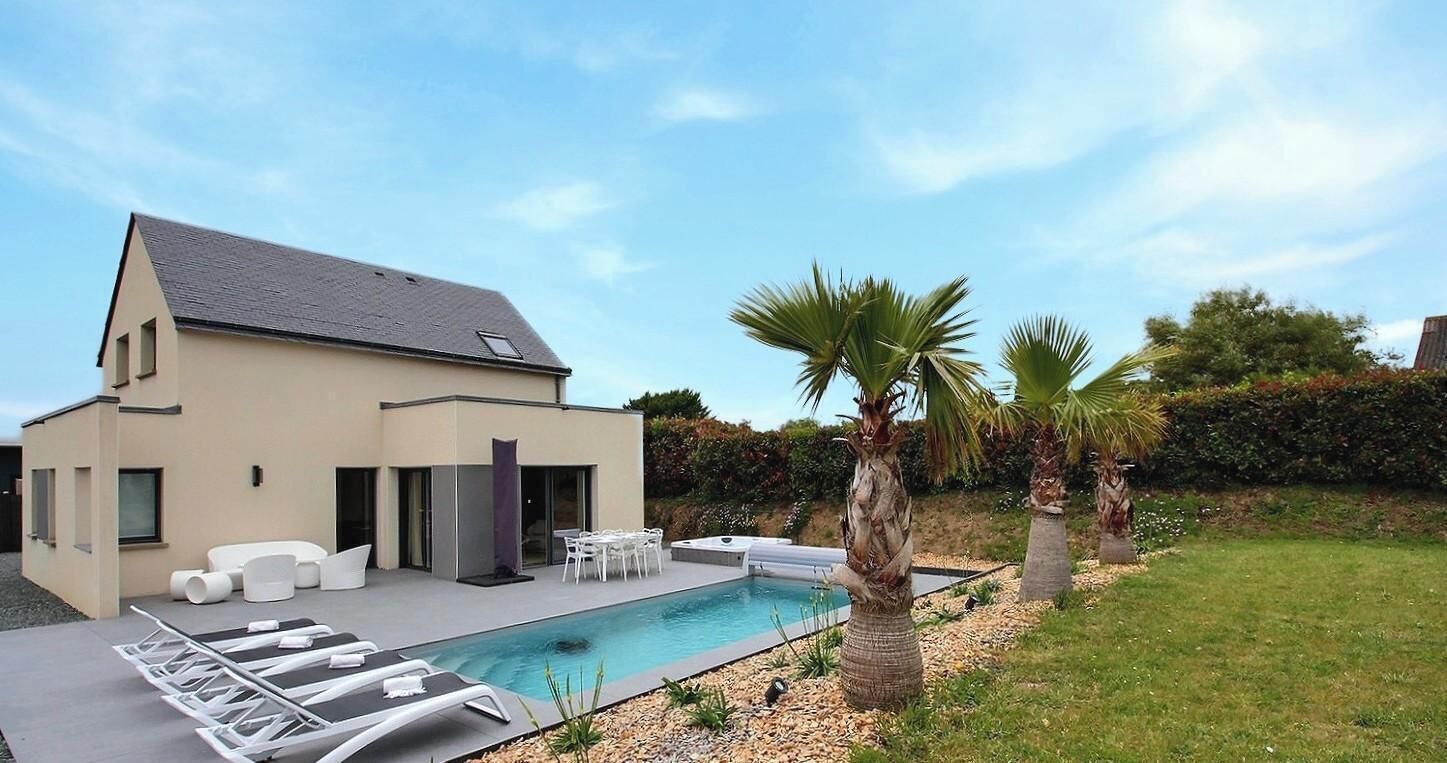 A modern house with a swimming pool, outdoor seating, and palm trees.