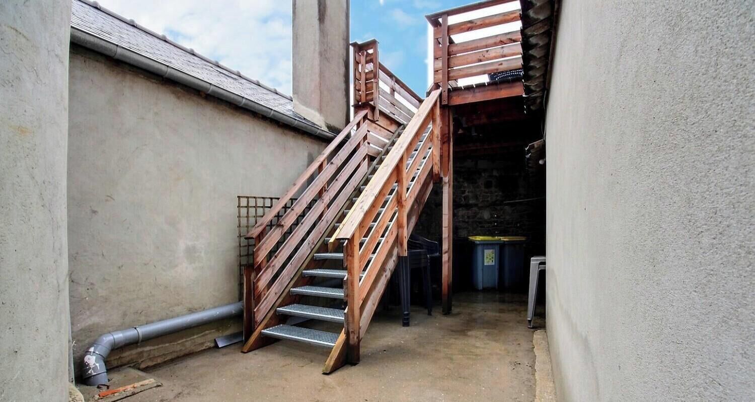 Eine enge Treppe mit Holzwangen, die zu einer höheren Ebene führt.
