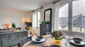 A dining area with a table set for two, a sofa, a television, and a view of the outside. - On the quay - TREGUIER (TREGUIER)