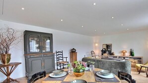 A dining area with a table set for four, a cabinet with glass doors, and a grey sofa in the background. - On the quay - TREGUIER (TREGUIER)