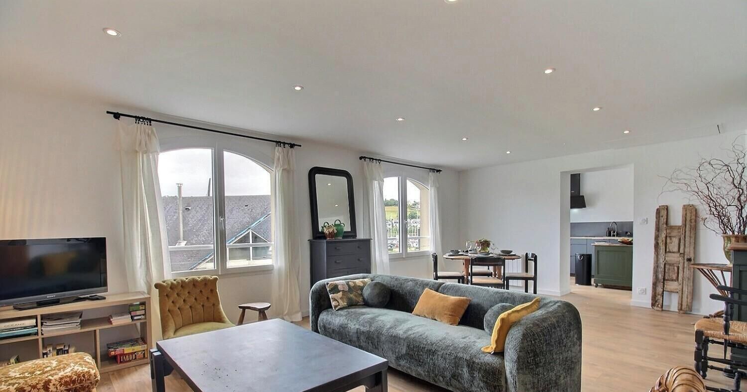 Ein geräumiges Wohnzimmer mit Sofa, Fernseher und Essbereich.