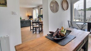 A modern dining area with a wooden table, a bowl of fruit, and a view of the kitchen and dining room in the background. - On the quay - TREGUIER (TREGUIER)