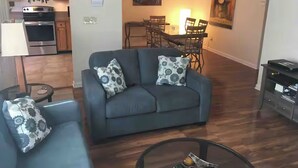 Ein Wohnzimmer mit einer Couch, einem Glastisch und einem Essbereich mit Stühlen und einem Tisch.