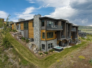 Ein modernes, mehrstöckiges Haus mit Natursteinfassade, großen Fenstern und einem Balkon.
