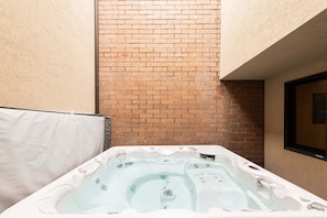 Ein Whirlpool in einer Ecke, mit Backsteinwand und Fenster.