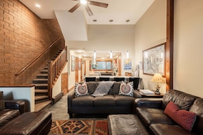 A spacious living area with a staircase, leather furniture, and a kitchen in the background. - Park City townhome with 2 bedrooms, den, and 3 baths. (Park City)