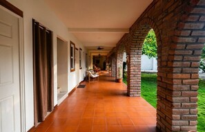 A corridor with a brick archway, white doors, and a tiled floor leading to a seating area with chairs. - Garden Beach 1-Bedroom with Hot Water & AC in La Costa del Sol (San Luis La Herradura)
