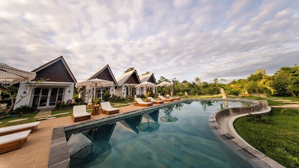 A resort with a swimming pool, lounge chairs, and overwater bungalows. - Lavanaa Nila-Luxury Resort (Penida Island)