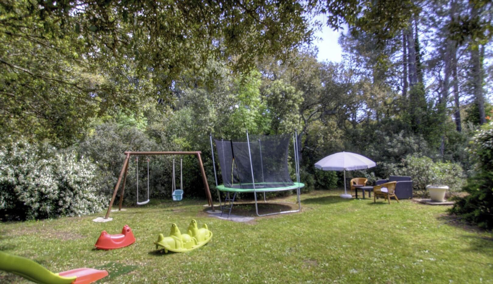 Ein Garten mit Schaukel, Trampolin und Gartenmöbeln.
