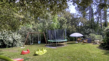 Ein Garten mit Schaukel, Trampolin und Gartenmöbeln.