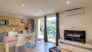 A modern kitchen with a dining area, a flat-screen TV, and a sliding glass door leading to an outdoor patio. - Villa I Pini - PORTO VECCHIO (PORTO VECCHIO)