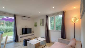 Ein modernes Wohnzimmer mit Flachbildfernseher, Sofa, Couchtisch und Stehlampe.