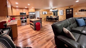 A modern kitchen with wooden cabinets, stainless steel appliances, and a dining area with a leather couch. - B & T's Garden Getaway-Located in Historic Parowan near Brianhead Ski Resort (Parowan)