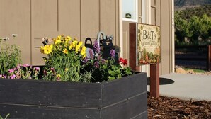 A wooden planter box with a variety of flowers in front of a building with a sign that reads 'B&T's Garden Retreat'. - B & T's Garden Getaway-Located in Historic Parowan near Brianhead Ski Resort (Parowan)