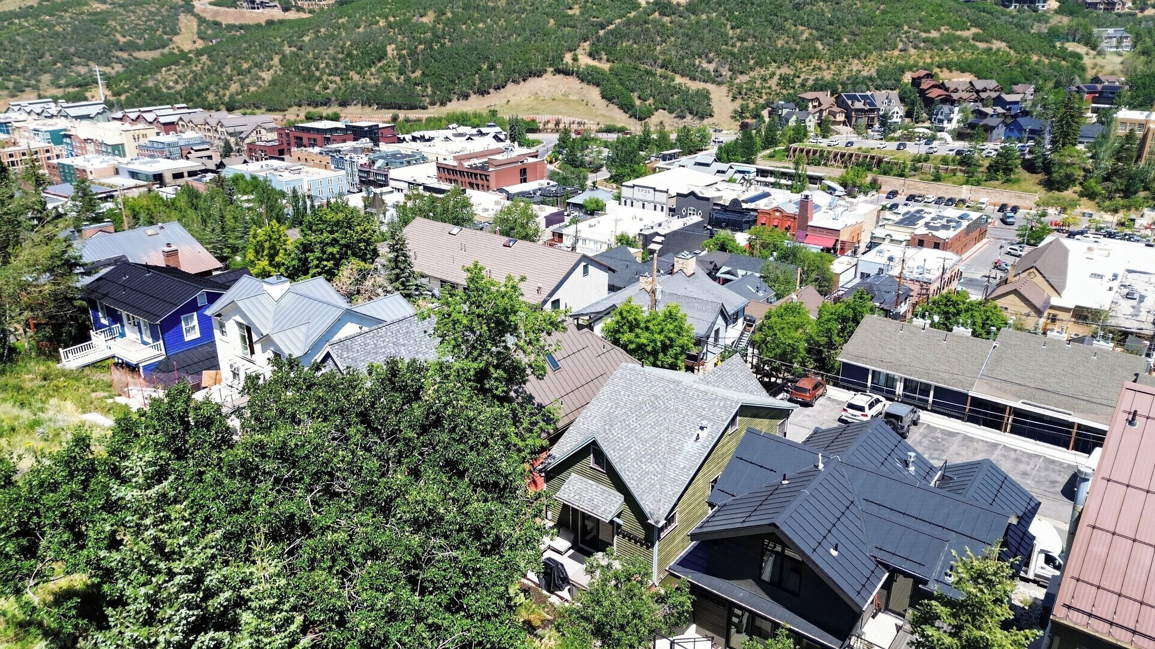Et boligområde med forskellige husstyles, både moderne og traditionelle, omgivet af grønt og kuperet terræn.