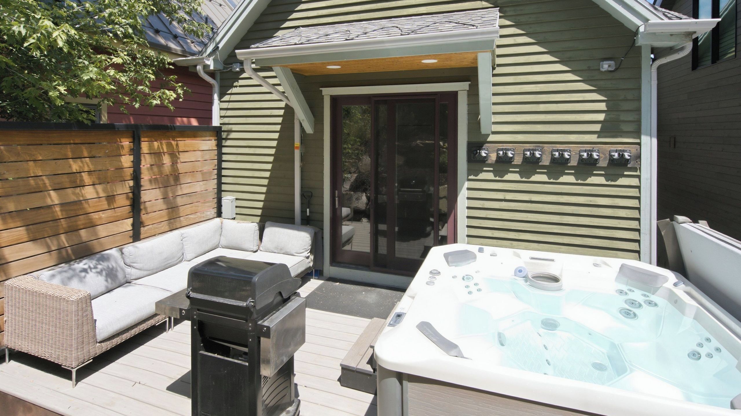 En terrasse med jacuzzi, sofa og grill.
