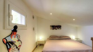 Ein Schlafzimmer mit einem Bett, einem Nachttisch, einem Wandbild und einer Mannequin.