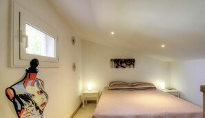 Ein Schlafzimmer mit einem Bett, einem Nachttisch, einem Wandbild und einer Mannequin.