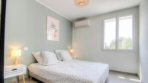 Una camera da letto con un letto, lampade da comodino, un condizionatore d'aria, una finestra e un quadro appeso al muro.