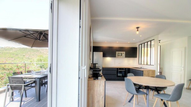 Una cucina moderna con mobili scuri, un forno a microonde e un tavolo da pranzo in legno con sedie.