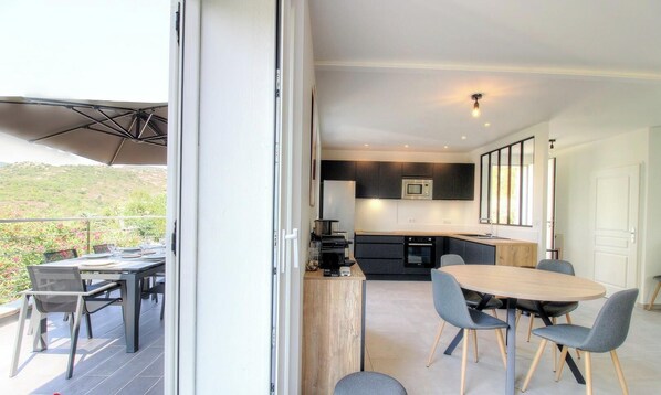 A modern kitchen with dark cabinets, a microwave, and a wooden dining table with chairs. - A casa Tomi - SERRA DI FERRO (SERRA DI FERRO)