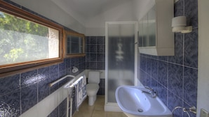 Ein Badezimmer mit Dusche, Toilette, Waschbecken und Fenster.