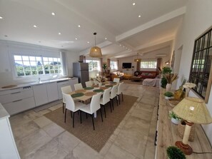 A spacious living area with a dining table, sofas, and a kitchen in the background. - Capana - SARTENE - Gîte (SARTENE)
