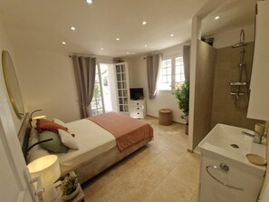 A bedroom with a bed, a TV, a bathroom with a sink and shower, and a window with curtains. - Capana - SARTENE - Gîte (SARTENE)