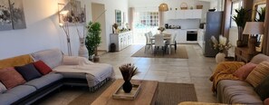 A modern living room with a sofa, a coffee table, and a dining area with chairs and a table. - Capana - SARTENE - Gîte (SARTENE)