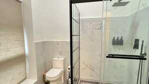 Un baño moderno con ducha de vidrio, inodoro y zona de lavamanos.