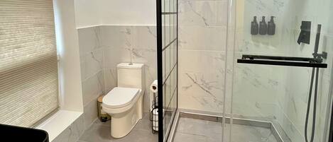 Un baño moderno con ducha de vidrio, inodoro y zona de lavamanos.