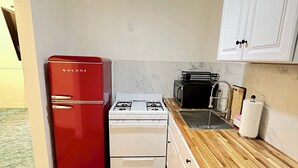 Una cocina compacta con un refrigerador rojo, estufa blanca y encimera de madera.