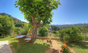 Ein Garten mit Tisch, Stühlen, einem Baum und Blumentöpfen.