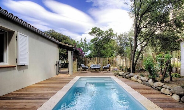 A rectangular swimming pool with a wooden deck, surrounded by a wooden fence and trees. - Travu Valley 2 (VENTISERI)