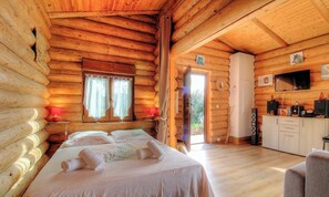 Eine Blockhütte mit Bett, Schreibtisch und Fernseher.