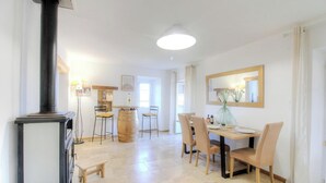Zona pranzo con tavolo e sedie in legno, un grande specchio e una cucina a gas nera.