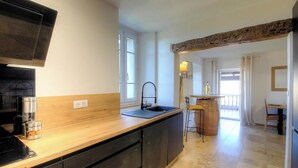 Cucina con piano di lavoro in legno, lavello e angolo bar con uno sgabello.