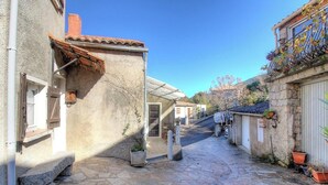 Una stretta strada acciottolata fiancheggiata da edifici, un cielo azzurro limpido e piante in vaso.
