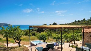 A patio with a hot tub, outdoor seating, and a view of the sea.