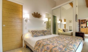 Ein Schlafzimmer mit einem Bett, einer Holztür, einem Spiegel und einer Wandleuchte.
