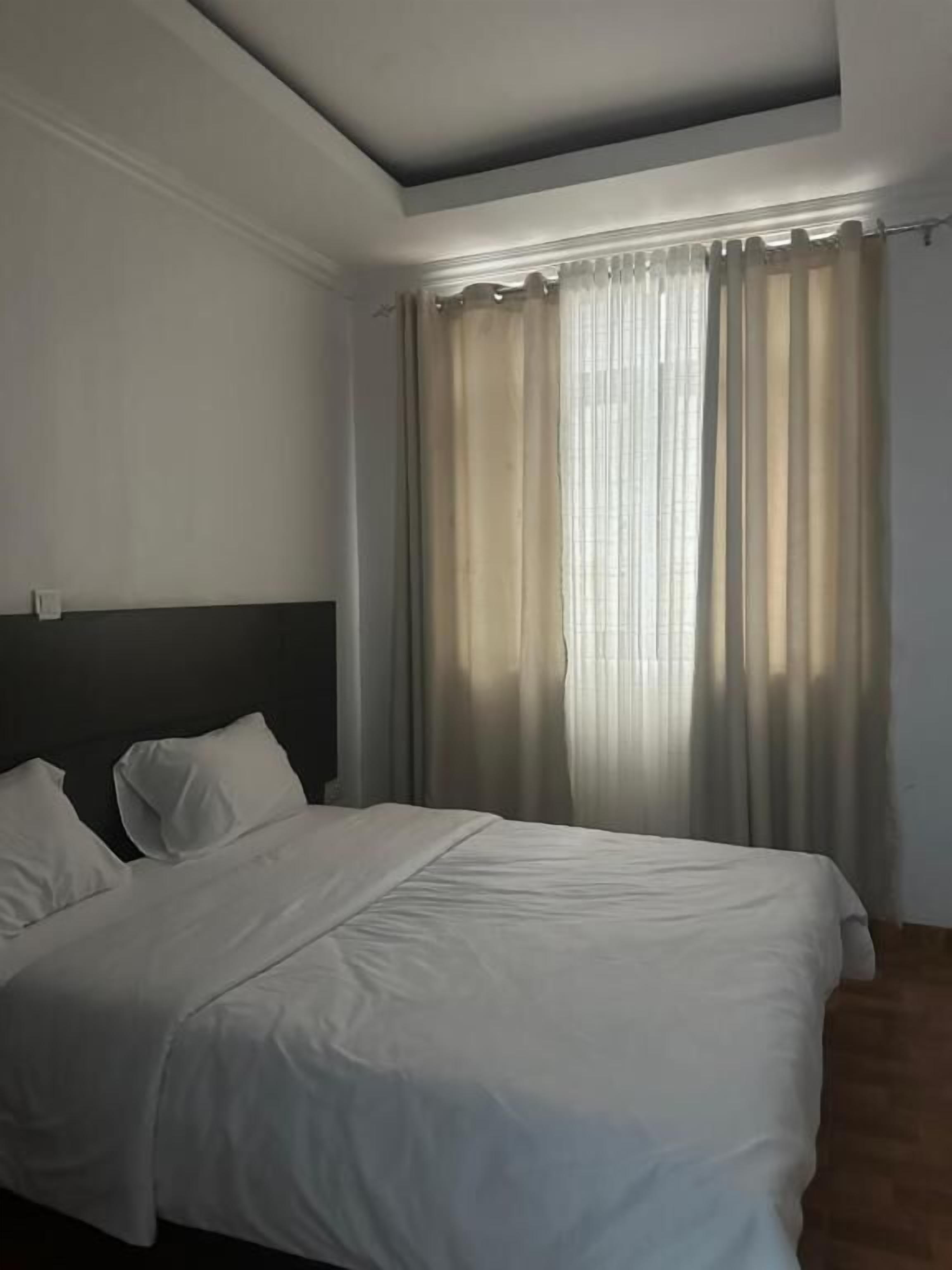 Ein Schlafzimmer mit Bett, Vorhängen und einem Kopfteil.