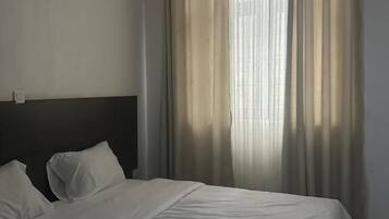 Ein Schlafzimmer mit Bett, Vorhängen und einem Kopfteil.