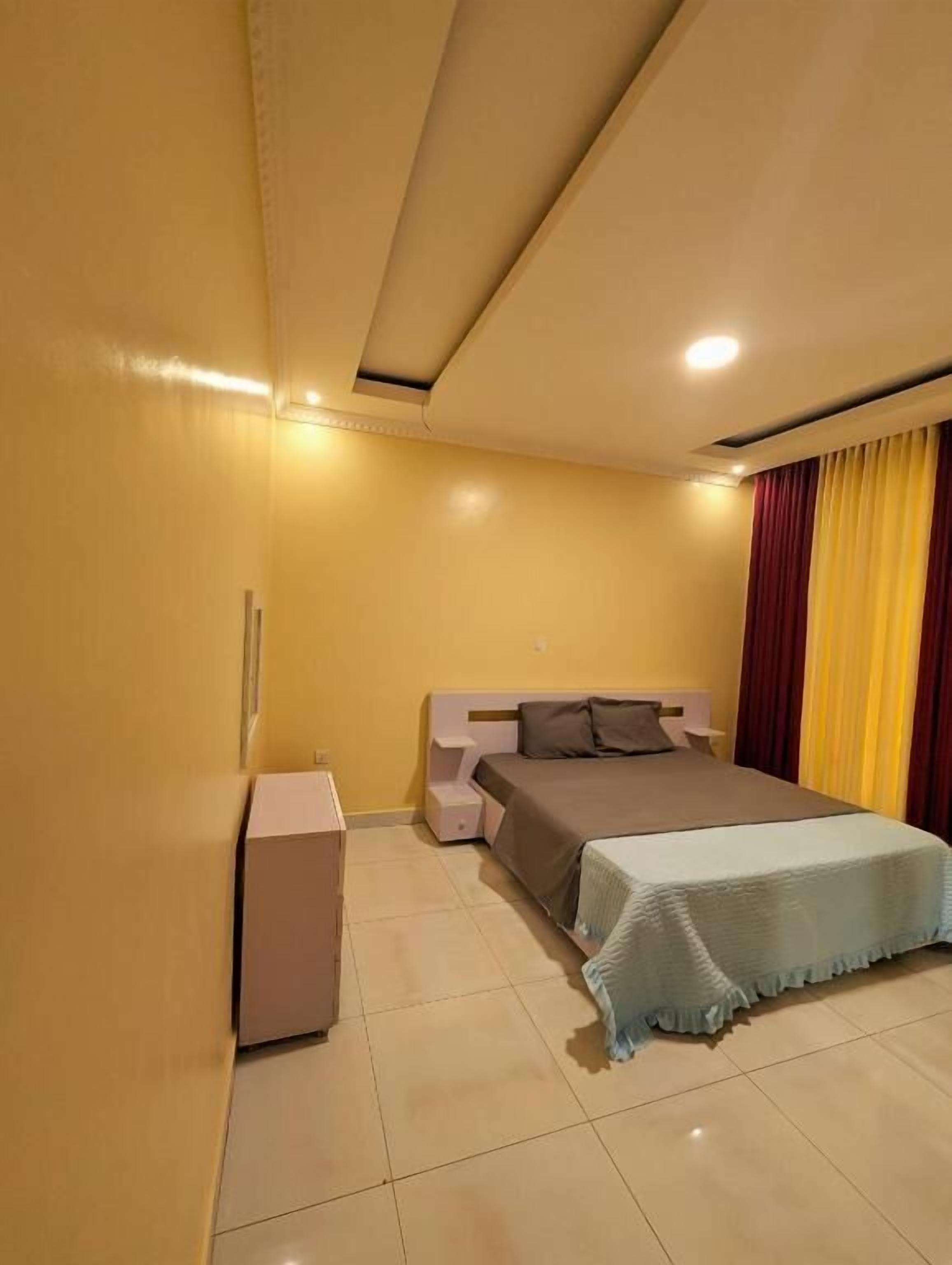 Un dormitorio con cama, mesitas de noche, armario y luz en el techo.