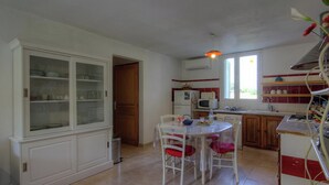 A kitchen with a dining table, chairs, cabinets, a microwave, and a window. - PAMPASGIOLU - PRUNELLI DI FIUM'ORBO (PRUNELLI DI FIUM'ORBO)