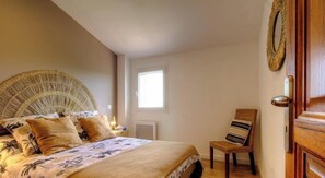Ein Schlafzimmer mit Bett, Stuhl, Fenster und Tür.