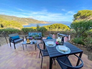 Eine Außenpatio mit Esstisch, Stühlen und einer Couch, mit Blick auf eine malerische Landschaft.