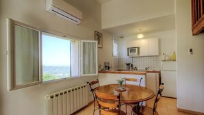 Une cuisine équipée d’une table à manger, de chaises, donnant sur une fenêtre et comprenant les appareils de cuisine de base.