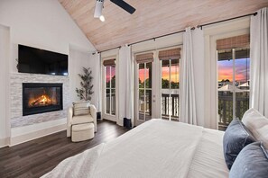 Ein Schlafzimmer mit Kamin, einem Bett, einem Sessel und großen Fenstern mit Ausblick.