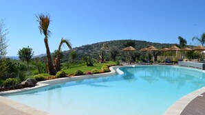A swimming pool with lounge chairs and umbrellas, surrounded by greenery and a hilly landscape. - Tivella House - TIZZANO (TIZZANO)
