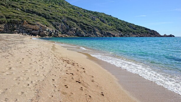 A beach with clear blue water, sandy shore, and a rocky hillside in the background. - Tivella House - TIZZANO (TIZZANO)